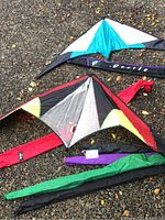 Photo showing three different kites laid on gravel surface with their corresponding kite bags