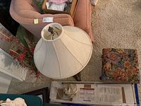 Overhead view of table lamp with fabric shade, rolling ottoman with floral pattern, faux plants with red flowers, and art light.