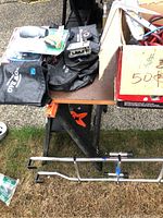 RV accessories including black tow bag, coiled wiring, connectors, and sewer hose on tabletop and in a cardboard box.