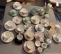 Full assortment of tea cups, saucers, cream and sugar set, and tea pot displayed on table.