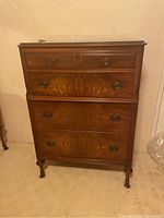 Front view of vintage wood dresser with four drawers and metal handles showing wood grain and finish.