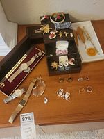 Overview of lot with Citizen watch, assorted pins, rings, earrings, and hook needles on wooden surface