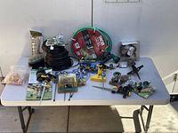 Full lot displayed on white folding table showing all items including tubing, hose, sprinklers, nozzles, and fittings.