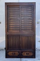 Front view of two-part tansu chest with sliding louvered doors and base drawers.