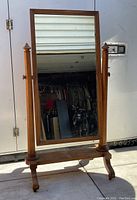 Front-facing view of full-length mirror showing wooden frame, turned posts, and base