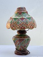 Full view of hand painted camel skin lamp showing detailed colorful patterns on base and lampshade.