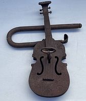 Front view of the violin-shaped cast iron lock with key inserted and U-shaped shackle showing rust and weathering.