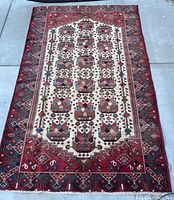Full view of the Persian Oriental rug showcasing geometric floral motifs on a cream and red background with a detailed border.