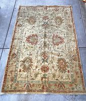 Top-down view of full Persian rug showing central floral motifs with soft yellow background and decorative border.