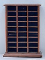 Front view of wooden cubby hole box showing 27 individual compartments arranged in three columns and nine rows with natural wood finish and rounded molding on base and top.