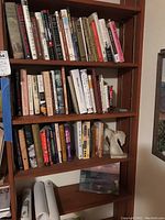 Books arranged on wooden bookshelf showing various book titles and a white horse head bookend on one shelf.