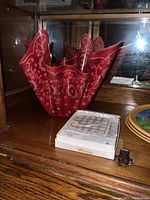 Red bandana bowl displayed with a closed white box and a small dark object on a wooden surface.