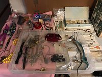 Full overview of all costume jewelry, watches, pins, and bolo ties spread on table.