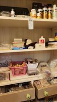 Wide view of wooden craft storage cabinet filled with assorted craft supplies including paints, wooden cut pieces, and containers.