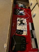 Drones and controllers placed in original packaging showing two white drones, one black drone, and controller units