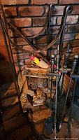 Log rack holding pieces of firewood with attached basket, broom and fireplace tools visible in front.