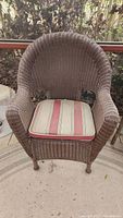 Front view of brown resin wicker armchair with striped cushion.