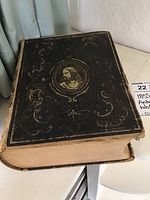Top view of the black leather cover of the antique Bible showing embossed design and central portrait.