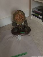 Full view of clock on wood base showing figural supports and key in front