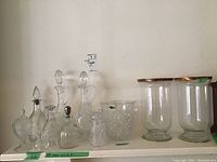 Shelf with all eleven items arranged: four decanters, wine cooler, two larger vases with rims, three containers