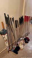 Full overview of umbrella, golf clubs, headcovers lined up against wall