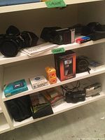 Shelf view showing various cameras, binoculars, clock, film, manuals, and accessories