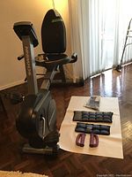 Full view of Schwinn recumbent bike with workout weights and manuals on floor nearby