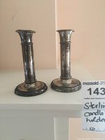 Pair of sterling silver candle stick holders seen side by side showing overall shape and size.