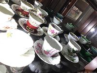 Photo showing multiple teacups and saucers arranged with various floral designs and gold accents.