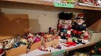Full view of assorted Christmas ornaments and figurines including nutcrackers and boxed ornaments on wooden shelf