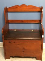 Full front view of wooden hall bench showing backrest, seat, and storage base with hinges on top of seat.
