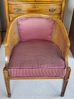 Frontal view of vintage wooden cane barrel back chair with striped cushioned seat and backrest