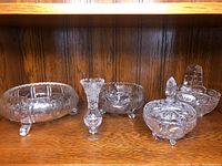 Front view of entire set showing large bowl, small bowl, candle holder, covered dish, and basket on wooden shelf