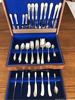 Wooden presentation chest open showing two upper trays of silverware