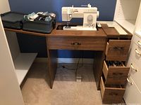 Singer sewing machine and wooden desk with drawers from front view, showing desk drawers and sewing machine top.