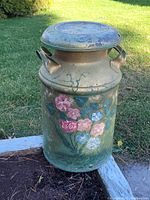 Front angle showing the hand-painted floral folk art on metal milk can with handles and lid.