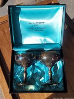 Two sterling silver wine goblets in blue silk-lined box with W.A. Rogers by Burk & Wallace imprint on lid.