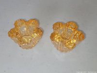 Top view of the pair of marigold carnival glass candle stick holders showing scalloped edges and flower-like shape.