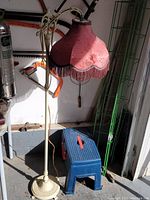 Full view of the cream painted cast iron standing lamp with pink fabric lampshade, showing height and overall condition.