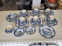 Full set of Churchill china arranged showing cups, saucers, plates, and bowls with detailed blue and white pattern.