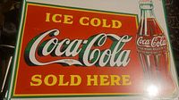 Front view of a rectangular metal Coca-Cola sign, showing the full logo, text, and vintage Coke bottle image with minor scratches.