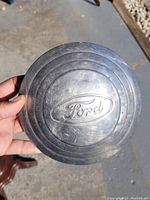 View of vintage Ford hub center cap showing logo and surface wear