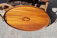 Top view of oval solid mahogany tray showing smooth finish, brass handles, and decorative inlay.