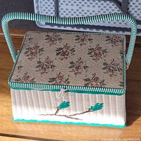 Full exterior view of the vintage sewing basket showing woven texture, floral fabric lid, turquoise and white color scheme, and handle.