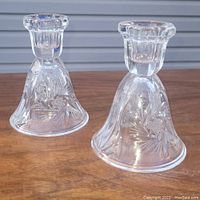 Pair of clear crystal candle holders with pinwheel cut patterns, standing upright on wooden surface