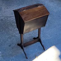 Closed antique solid walnut sewing stand showing exterior top and base with curved legs