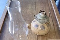 Close-up image showing the glass chimney next to the stoneware pottery lamp base with metal burner and wick.