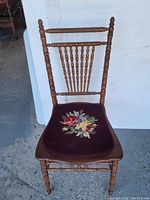 Full front view of the Victorian maple chair with detailed needlepoint floral cushion on seat.