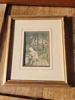 Front view of the vintage romantic print framed in a gold wooden frame with matting, showing detail of the woman seated on a bench in a garden path setting.