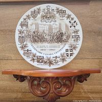 Front view of the commemorative Wood & Sons ironstone plate on the decorative wooden wall shelf showing detailed Canadian Confederation design with provincial coats of arms.